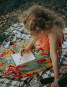 woman in orange tank top sitting on white and black textile